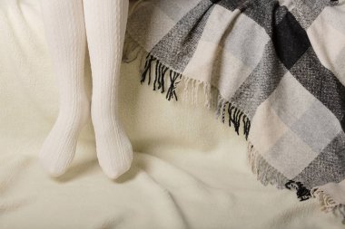 Beyaz bir arka plan üzerinde sıcak beyaz örme taytlı kadın bacakları faux kürk ürünleri.