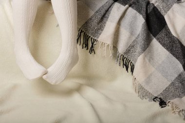 Beyaz bir arka plan üzerinde sıcak beyaz örme taytlı kadın bacakları faux kürk ürünleri.