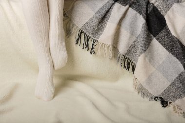 Beyaz bir arka plan üzerinde sıcak beyaz örme taytlı kadın bacakları faux kürk ürünleri.