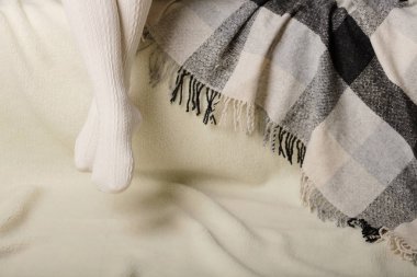 Beyaz bir arka plan üzerinde sıcak beyaz örme taytlı kadın bacakları faux kürk ürünleri.