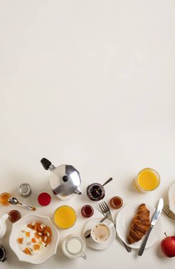 Kahvaltı zamanı. Kruvasan ve portakal suyu, reçel ve bal. Krema veya süt ile kahve. Meyve - muz, kırmızı ve yeşil elma. Ricotta ekşi krema, fındık ve kuru kayısı ile. Beyaz bir masaya servis kahvaltı. Yukarıdan görüntülemek.