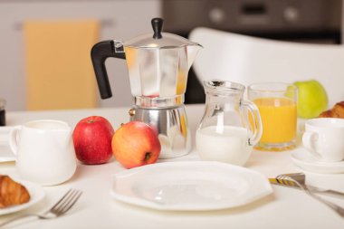 Kahvaltı zamanı. Kruvasan ve portakal suyu, reçel ve bal. Krema veya süt ile kahve. Meyve - muz, kırmızı ve yeşil elma. Beyaz bir masaya Servis Kahvaltı. 