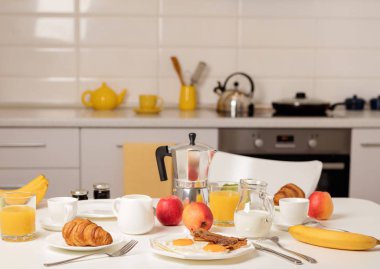 Kahvaltı zamanı. Kızarmış yumurta ve domuz pastırması. Kruvasan ve portakal suyu, reçel. Krema veya süt ile kahve. Meyve - muz, kırmızı ve yeşil elma. Beyaz bir masaya Servis Kahvaltı. 