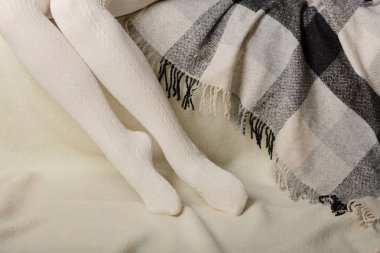 Beyaz bir arka plan üzerinde sıcak beyaz örme taytlı kadın bacakları faux kürk ürünleri.