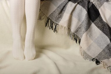 Beyaz bir arka plan üzerinde sıcak beyaz örme taytlı kadın bacakları faux kürk ürünleri.