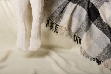 Beyaz bir arka plan üzerinde sıcak beyaz örme taytlı kadın bacakları faux kürk ürünleri.