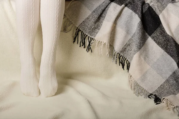 Beyaz bir arka plan üzerinde sıcak beyaz örme taytlı kadın bacakları faux kürk ürünleri.