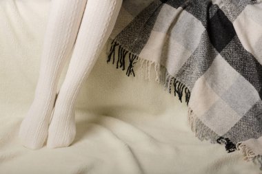 Beyaz bir arka plan üzerinde sıcak beyaz örme taytlı kadın bacakları faux kürk ürünleri.