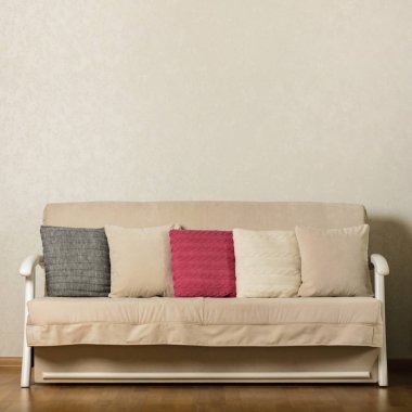 Bej kanepe oturma odasında renkli yastıklar (pembe, gri, beyaz) ile. Seçici odak.