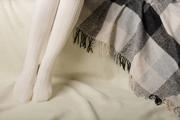 Beyaz bir arka plan üzerinde sıcak beyaz örme taytlı kadın bacakları faux kürk ürünleri.