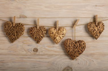 Sevgililer günün kutlu olsun! Hafif ahşap arka plan üzerinde altın rengi dekoratif hasır kalpleri. Seçici odak.