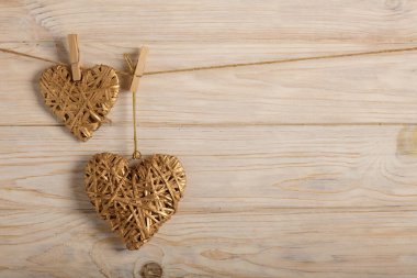 Sevgililer günün kutlu olsun! Hafif ahşap arka plan üzerinde altın rengi dekoratif hasır kalpleri. Seçici odak.