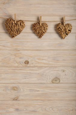 Sevgililer günün kutlu olsun! Hafif ahşap arka plan üzerinde altın rengi dekoratif hasır kalpleri. Seçici odak.