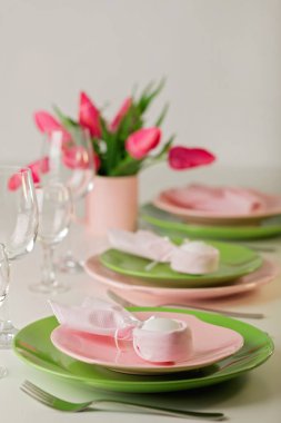 Mutlu Paskalyalar. Dekor ve Paskalya tablonun tablo ayarını pembe laleler ve yemekleri pembe ve yeşil renk ile bir vazo var. Seçici odak.