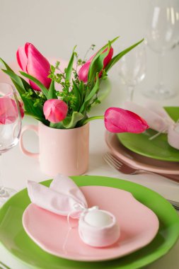 Mutlu Paskalyalar. Dekor ve Paskalya tablonun tablo ayarını pembe laleler ve yemekleri pembe ve yeşil renk ile bir vazo var. Seçici odak.