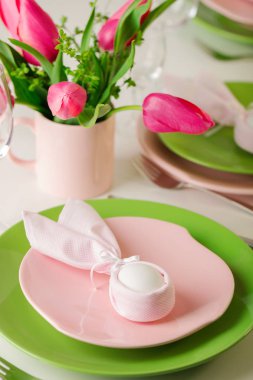 Mutlu Paskalyalar. Dekor ve Paskalya tablonun tablo ayarını pembe laleler ve yemekleri pembe ve yeşil renk ile bir vazo var. Seçici odak.