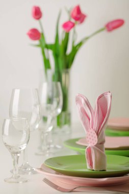 Mutlu Paskalyalar. Dekor ve Paskalya tablonun tablo ayarını pembe laleler ve yemekleri pembe ve yeşil renk ile bir vazo var. Seçici odak.