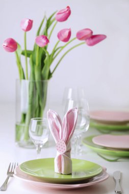 Mutlu Paskalyalar. Dekor ve Paskalya tablonun tablo ayarını pembe laleler ve yemekleri pembe ve yeşil renk ile bir vazo var. Seçici odak.