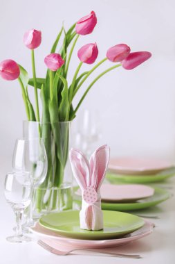 Mutlu Paskalyalar. Dekor ve Paskalya tablonun tablo ayarını pembe laleler ve yemekleri pembe ve yeşil renk ile bir vazo var. Seçici odak.