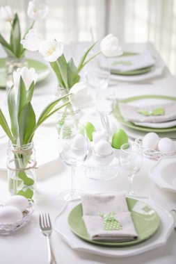 Paskalya tablonun Tablo ayarı ve dekor beyaz laleler ve yemekleri yeşil ve beyaz renk ile bir vazo var. Paskalya dekor ile beyaz lekeli. Seçici odak.