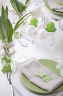 Paskalya tablonun Tablo ayarı ve dekor beyaz laleler ve yemekleri yeşil ve beyaz renk ile bir vazo var. Paskalya dekor ile beyaz lekeli. Seçici odak.