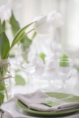 Paskalya tablonun Tablo ayarı ve dekor beyaz laleler ve yemekleri yeşil ve beyaz renk ile bir vazo var. Paskalya dekor ile beyaz lekeli. Seçici odak.