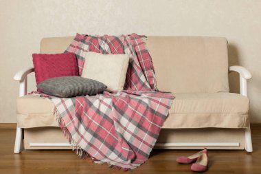 Bej kanepe ekose ve renkli yastıklar (pembe, gri, beyaz) ile ben