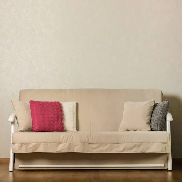 Beige sofa with colorful pillows (pink, grey, white) in the livi