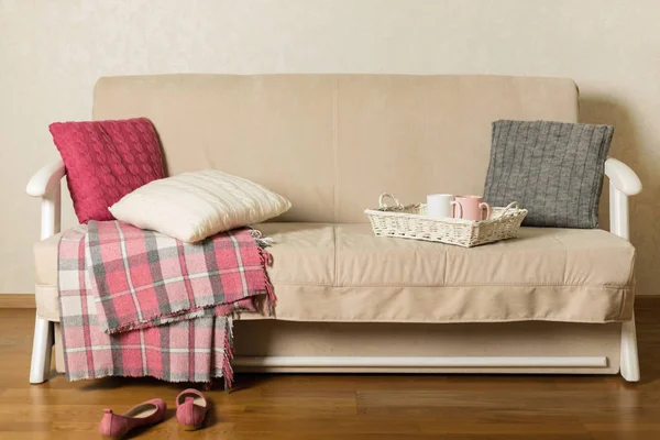 Beige sofa with plaid and colorful pillows (pink, grey, white) a