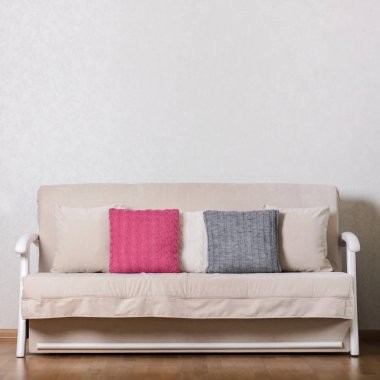 Livi (pembe, gri, beyaz) renkli yastıklar ile bej kanepe