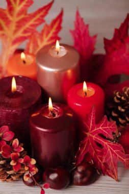 Sonbahar natürmort - arka planda mumlar, yapraklar ve koniler 