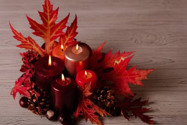 Sonbahar natürmort - arka planda mumlar, yapraklar ve koniler 