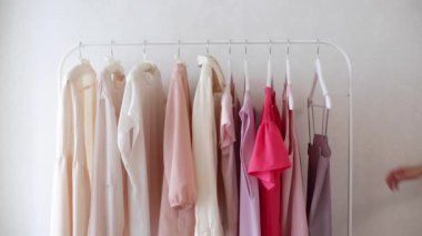 Beyaz bir askıda pembe, bej ve krem rengi gözlüklerle kadın kıyafetleri. Seçici odak.