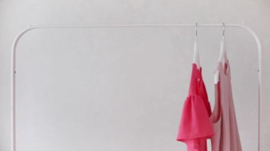 Beyaz bir askıda pembe, bej ve krem rengi gözlüklerle kadın kıyafetleri. Seçici odak.