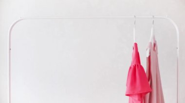 Beyaz bir askıda pembe, bej ve krem rengi gözlüklerle kadın kıyafetleri. Seçici odak.