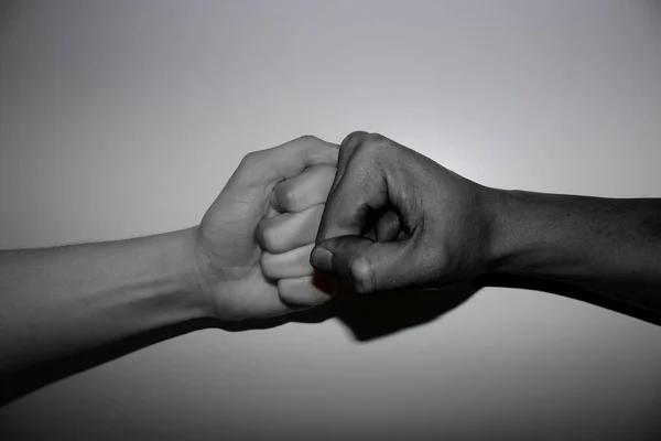 Hand gestures - Fist bump of two differenend - multi coloured hands in black and white