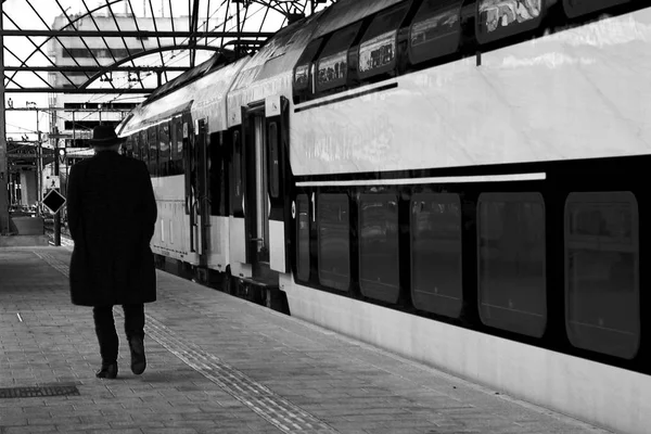 Velho caminhando ao longo de um trem de uma plataforma vazia que está viajando ou disse adeus a alguém - BW — Fotografia de Stock