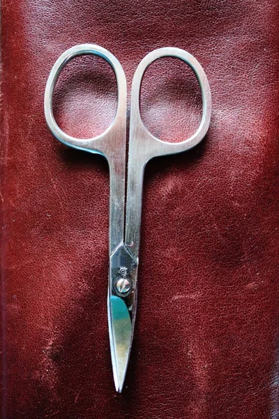 Close up of a scissor on a background of red leather — Stock Photo, Image