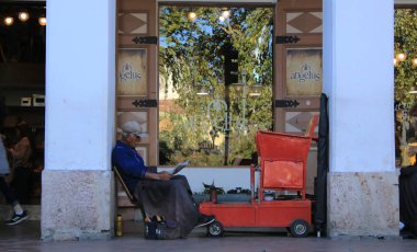 Cuenca - Ekvador, 2-5-2019:Bir müşterinin ayakkabı temizlemesini beklerken gazete okuyan yaşlı adam