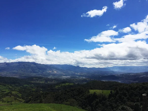 Bergblick mit wolkenverhangenem Himmel und der Stadt otavalo, ecuador im Tal — Stockfoto