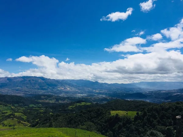 Bergblick mit wolkenverhangenem Himmel und der Stadt otavalo, ecuador im Tal — Stockfoto