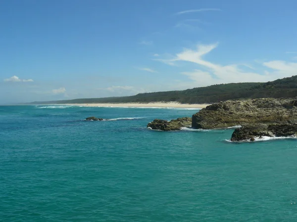 Vista de verde claro, baía azulada com uma praia branca e floresta no fundo — Fotografia de Stock