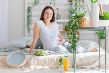 Genç hamile kadın hafif modern İskandinav yatak odası iç poz