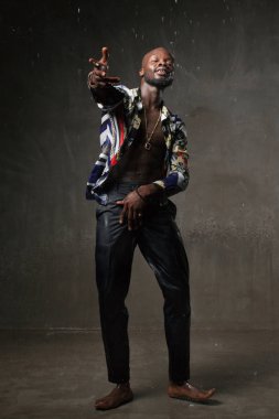 güçlü bir Afrikalı-Amerikalı genç adam gri beton zemin üzerine yağmur altında dans