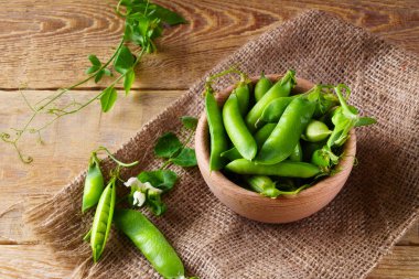 Tuval Jüt kumaş üzerine hafif ahşap kase taze çiğ yeşil bezelye