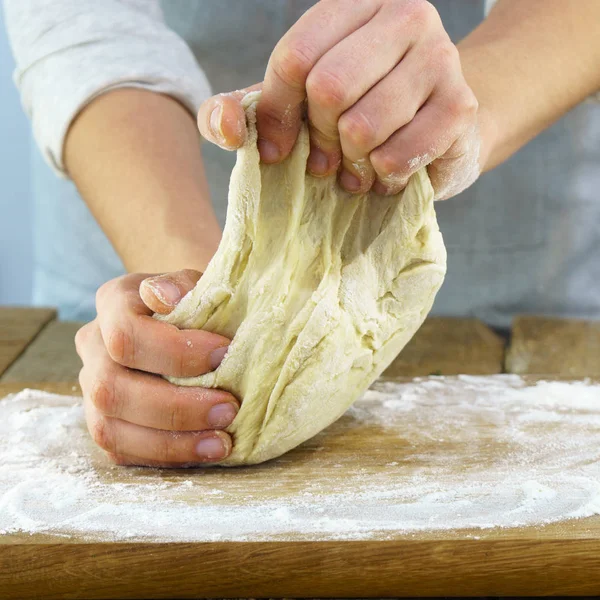Şef yoğurma çiğ hamur ahşap tahta üzerinde eller