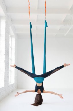 Genç kadın sinek yoga beyaz spor salonunda germe egzersizleri yaparken