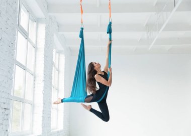 Genç kadın sinek yoga beyaz spor salonunda germe egzersizleri yaparken