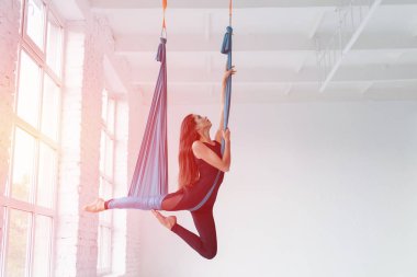 Genç kadın sinek yoga beyaz spor salonunda germe egzersizleri yaparken