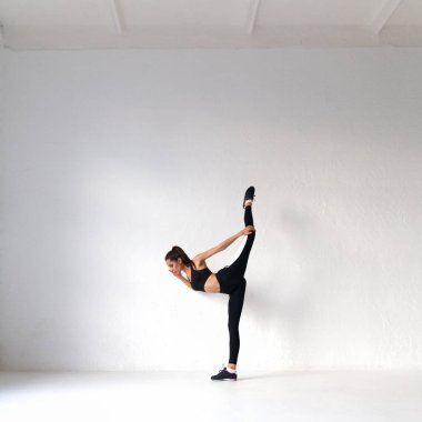 Genç kadın beyaz spor salonunda germe egzersizleri yoga yaparken